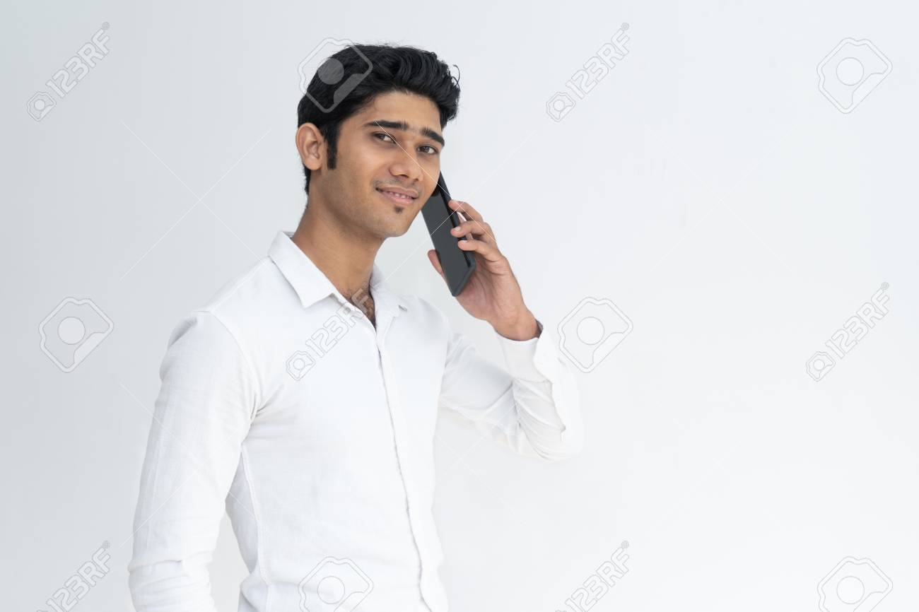 Positive Smiling Indian Guy Speaking On Mobile Phone Cheerful Young Handsome Male Student In White Shirt Talking On Cellphone Communication And Digital Devices Concept Stock Photo Picture And Royalty Free Image Image