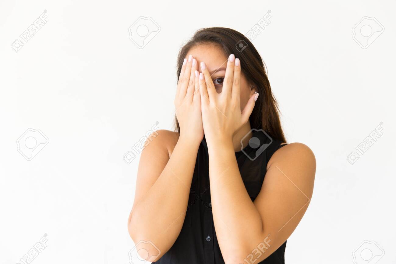 Tight cropped face of a scared young girl with hands covering