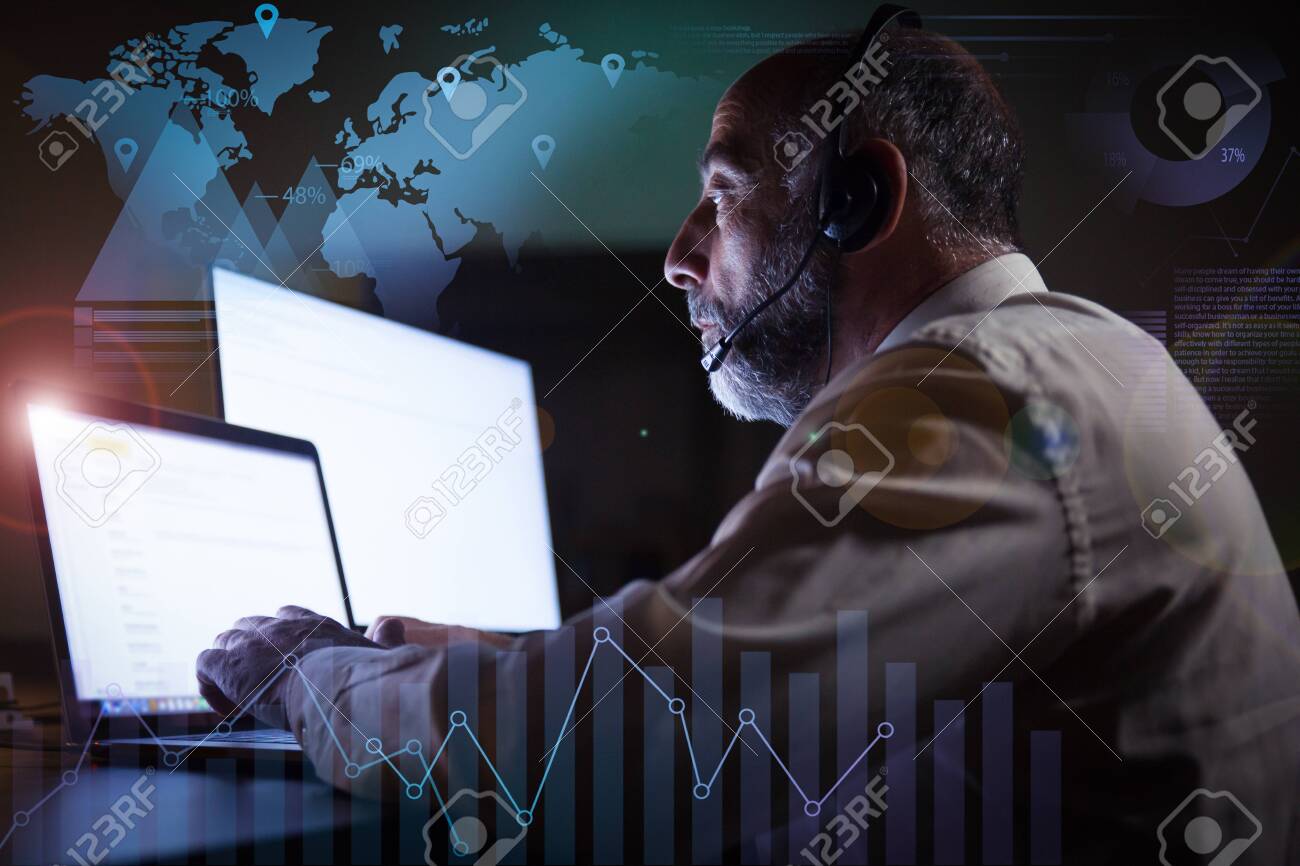 Man in headset using laptop and virtual statistic graphics. Side view of focused mature male call center operator in headset working with computer in dark office. Customer support concept - 144369055 Man in headset using laptop and virtual statistic graphics. Side view of focused mature male call center operator in headset working with computer in dark office. Customer support concept - 144369055