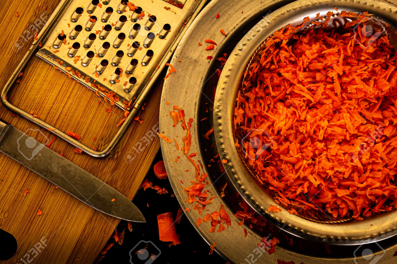 View of grated carrots in a bowl along with the grater and knife - 164966824 View of grated carrots in a bowl along with the grater and knife - 164966824