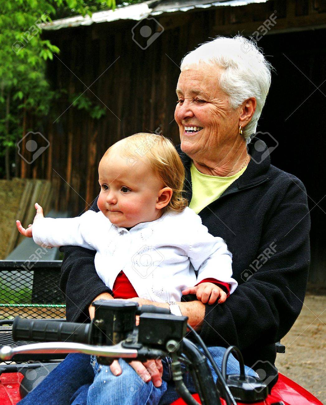 A toddler sits with her grandmother in front of a barn - 3223191 A toddler sits with her grandmother in front of a barn - 3223191