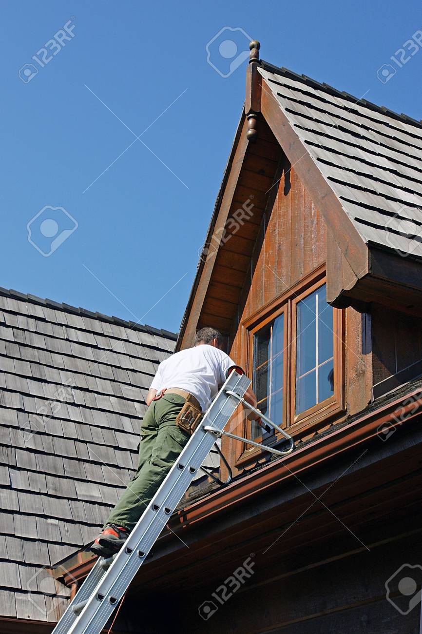 Painter on a ladder staining woodwork on a log home - 3616132 Painter on a ladder staining woodwork on a log home - 3616132