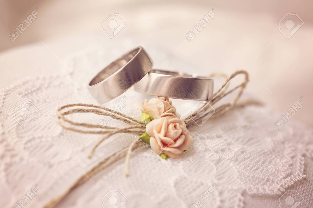 Wedding ring on lace pillow with sweet artificial small rose blossoms - 129082776 Wedding ring on lace pillow with sweet artificial small rose blossoms - 129082776