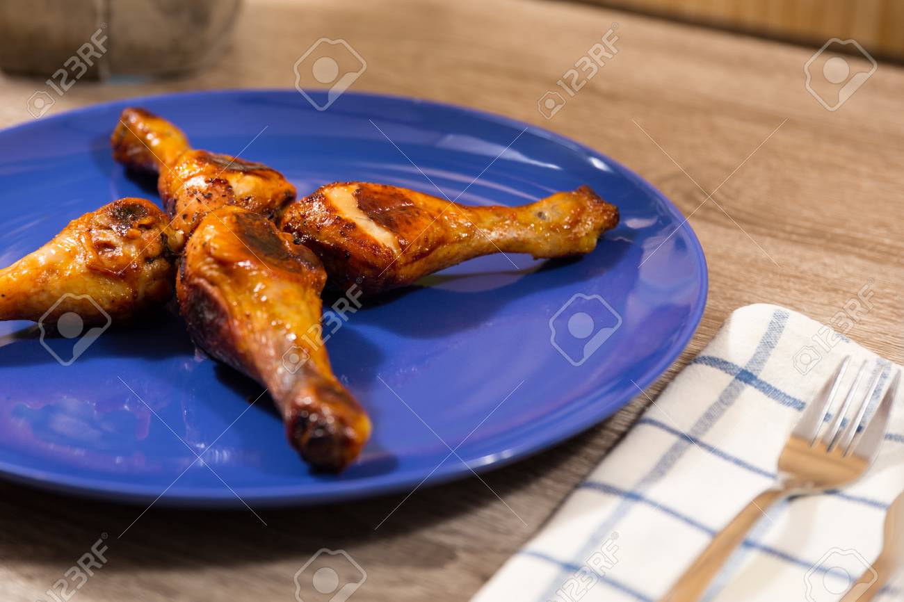 Four Chicken Drumsticks Marinated In Hot Sauce On A Blue Plate