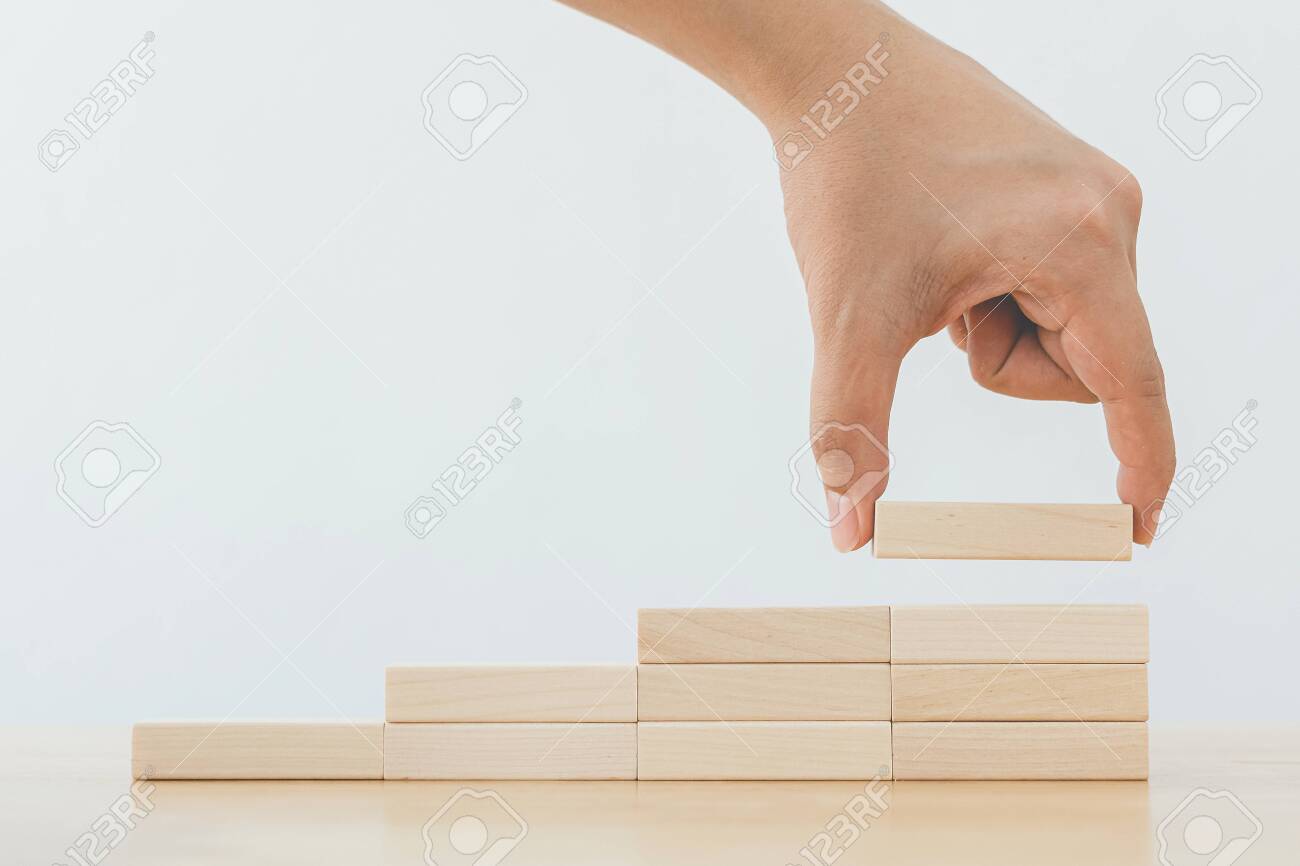 Hand arranging wood block stacking as step stair. Ladder career path concept for business growth success process - 146657846 Hand arranging wood block stacking as step stair. Ladder career path concept for business growth success process - 146657846