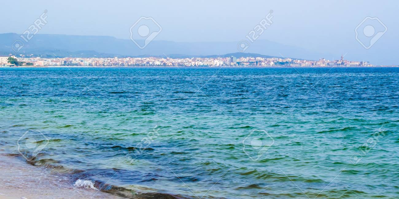 La Baia Di Alghero Con La Spiaggia Bianca E La Città Sullo Sfondo In Sardegna Italia