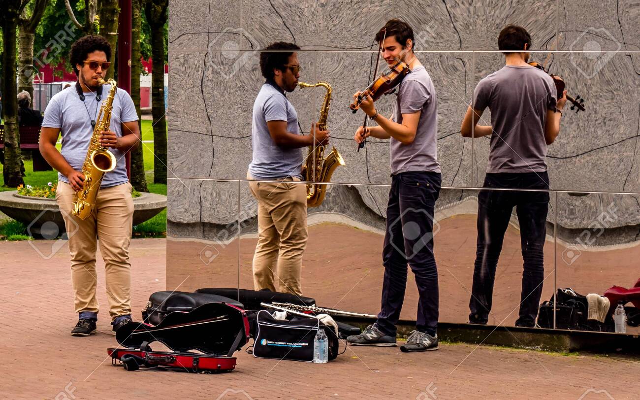street performer in amsterdam with reflection wall, playing violin and saxophon music - 140730769 street performer in amsterdam with reflection wall, playing violin and saxophon music - 140730769