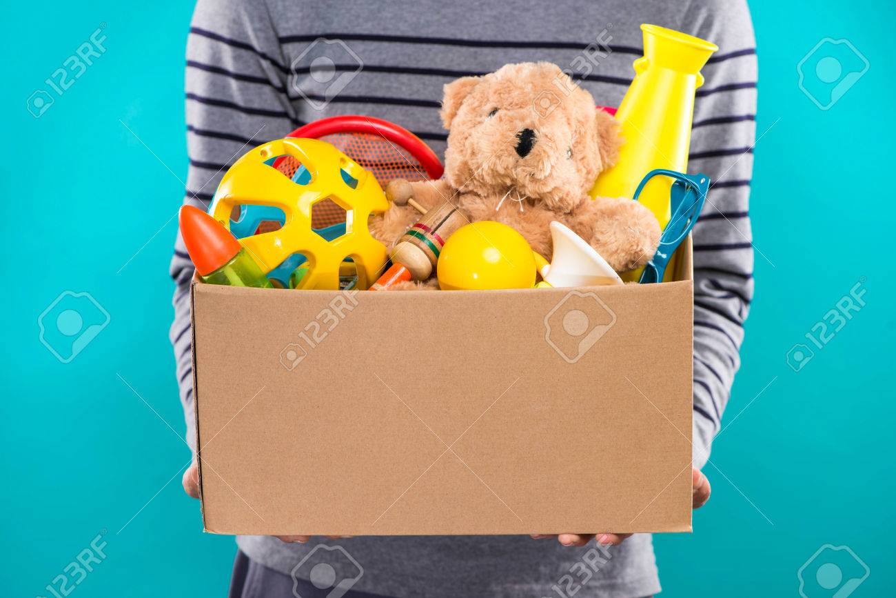 Male volunteer holding donation box with old toys. - 81072428 Male volunteer holding donation box with old toys. - 81072428