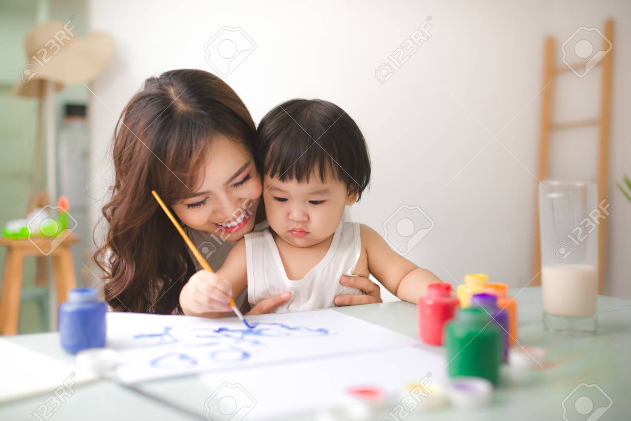 Happy family mother and daughter together paint. Asian woman helps her child girl. - 83236318 Happy family mother and daughter together paint. Asian woman helps her child girl. - 83236318