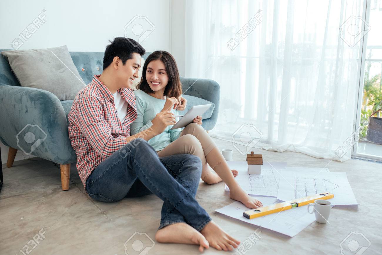 Attractive young asian adult couple looking at house plans. - 83251577 Attractive young asian adult couple looking at house plans. - 83251577