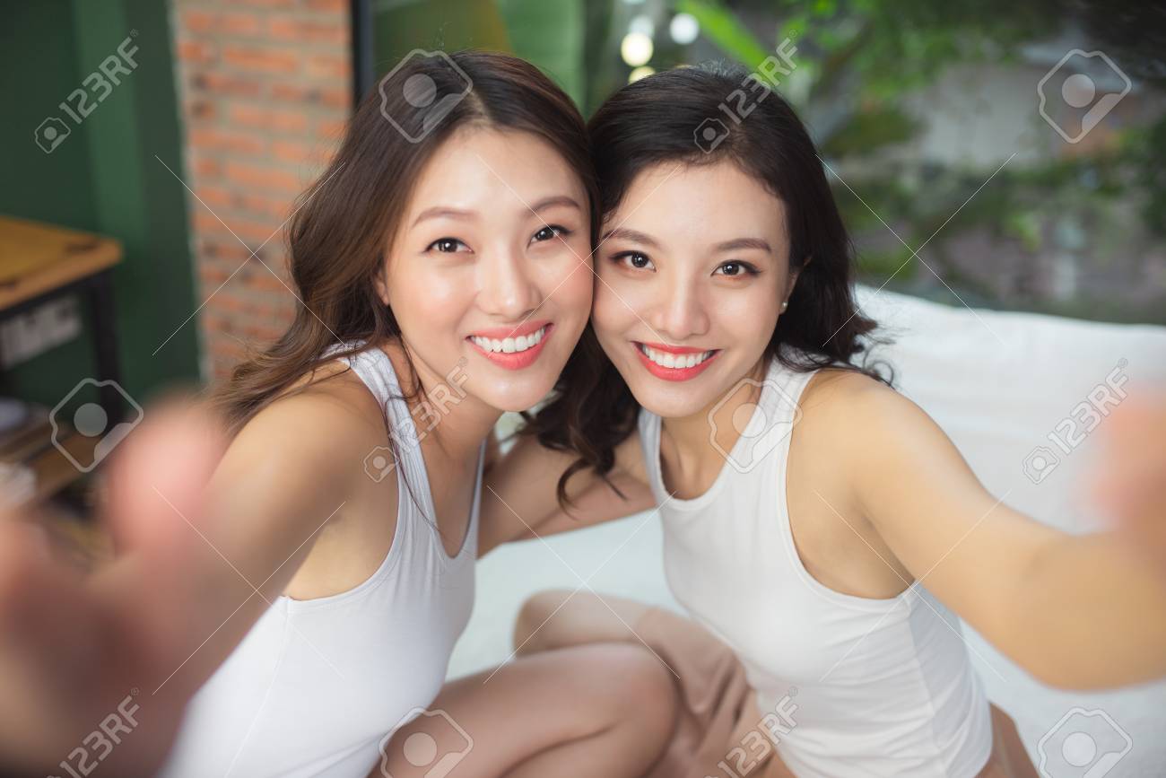Due Donne Asiatiche Nella Camera Da Letto Sul Letto Dipingono Le ... Due Donne Asiatiche Nella Camera Da Letto Sul Letto Dipingono Le ...