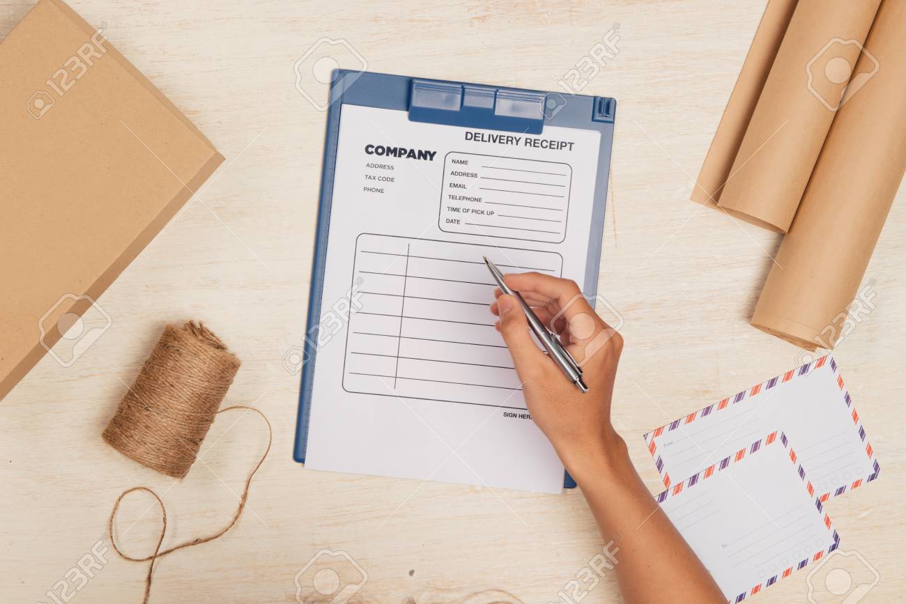 top view of deliveryman making notes in delivery receipt at table delivery receipt