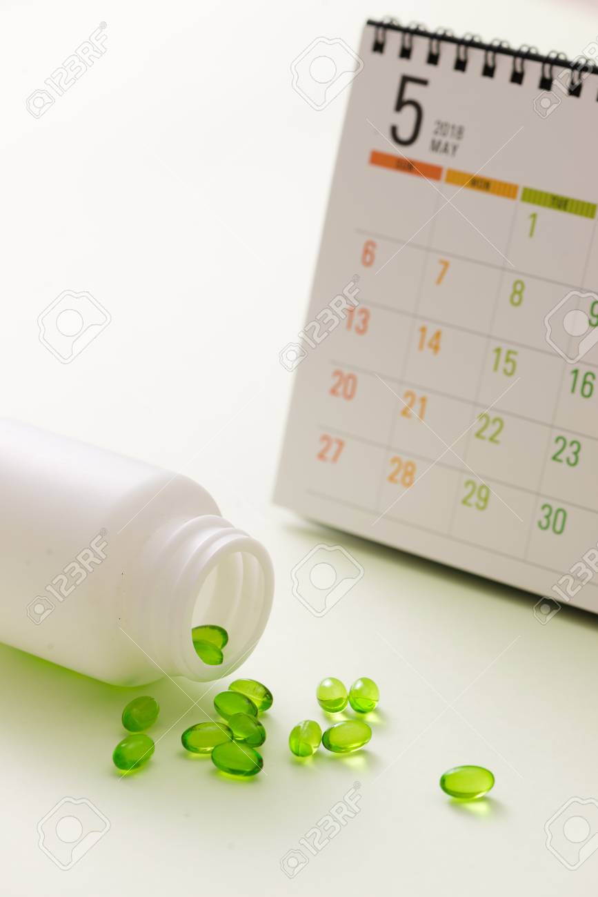 medical pills capsule in pill box with calendar on white background pill calendar
