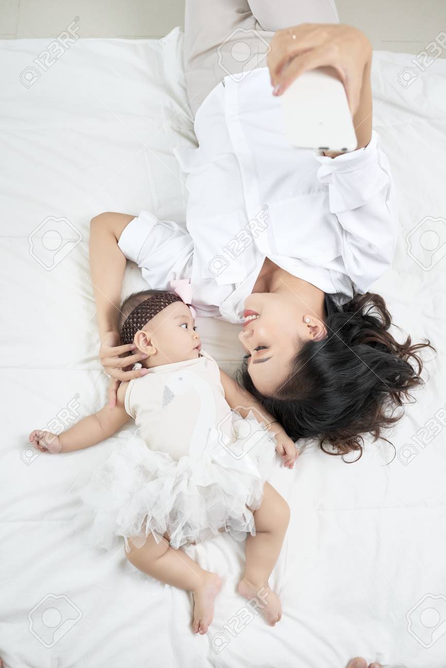 Young mother and cute baby on bed at home - 108467162 Young mother and cute baby on bed at home - 108467162