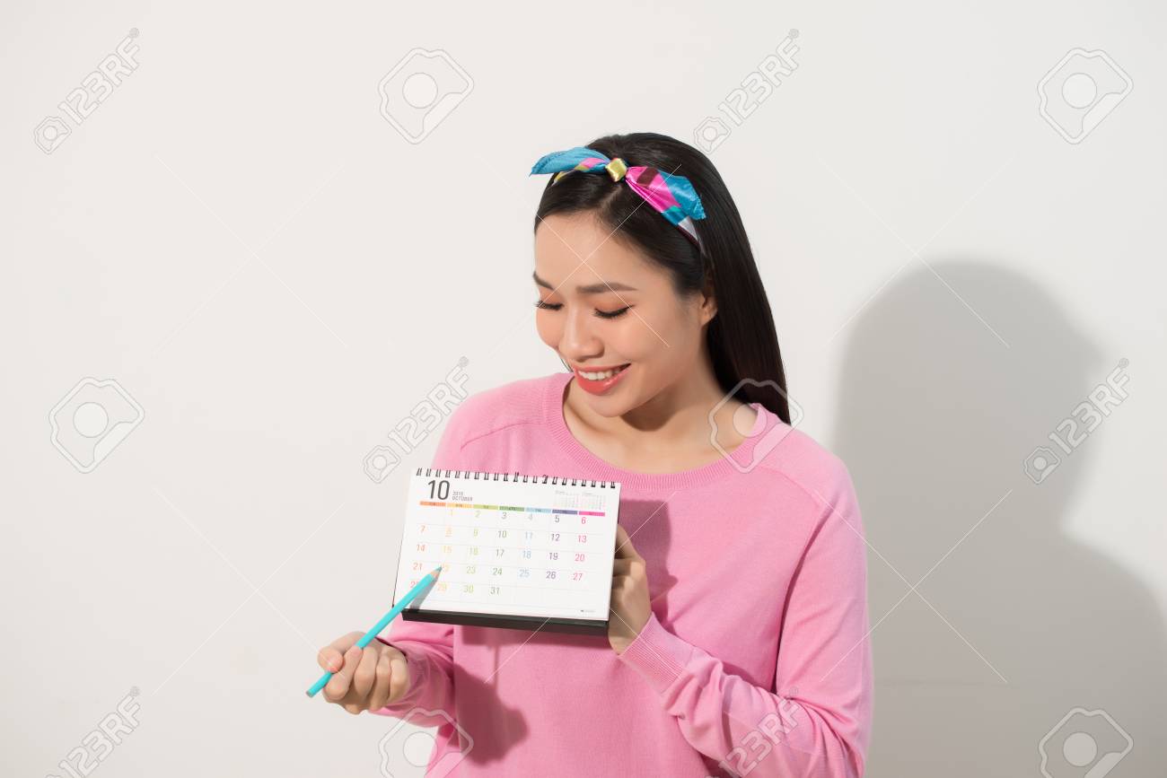 Portrait of a smiling young girl checking her periods according to calendar isolated over white background - 113653942 Portrait of a smiling young girl checking her periods according to calendar isolated over white background - 113653942
