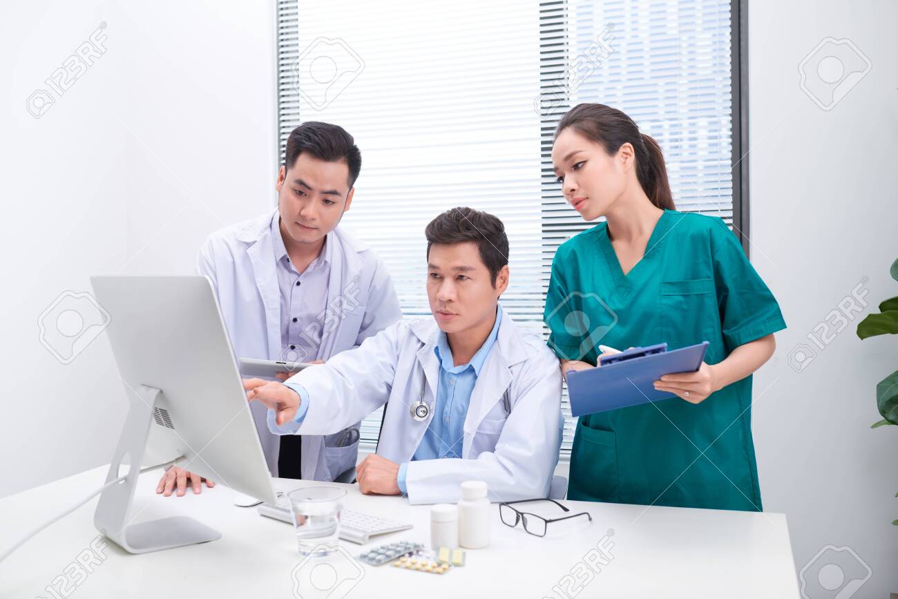 Three doctors discussing patient files on office. - 122835432 Three doctors discussing patient files on office. - 122835432