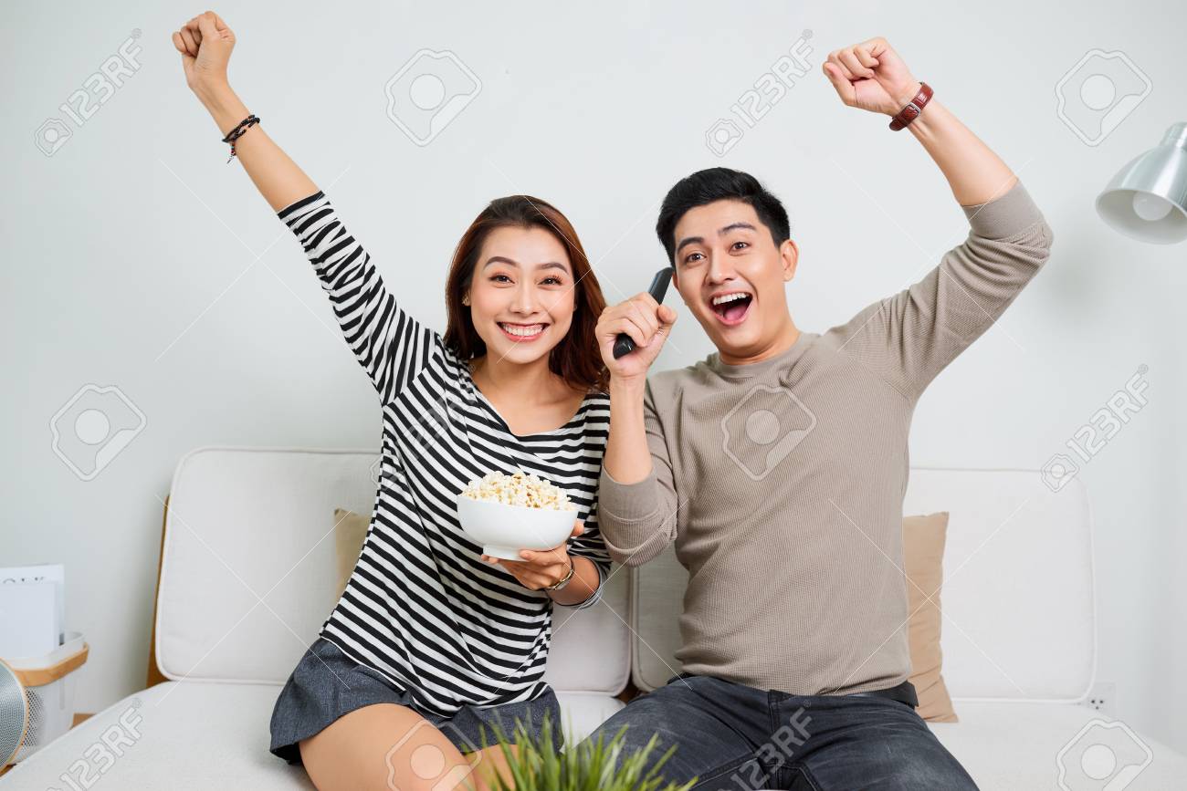 young handsome couple enjoying free time watching television with popcorn - 118567503 young handsome couple enjoying free time watching television with popcorn - 118567503