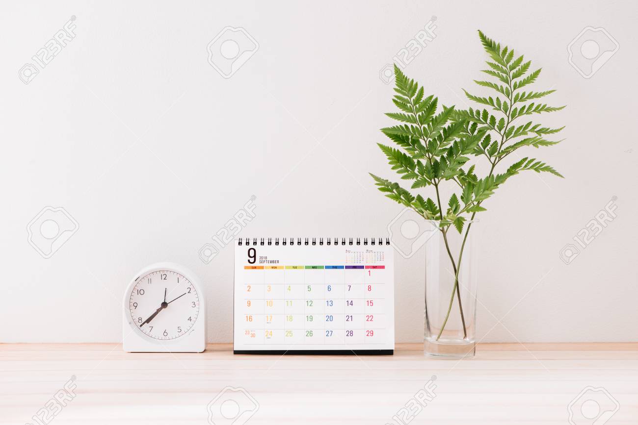 Mockup with a calendar with a white center against the background of a white wall with a alarm clock, leaves in vase - 121062989 Mockup with a calendar with a white center against the background of a white wall with a alarm clock, leaves in vase - 121062989
