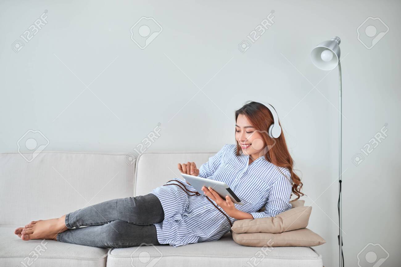 Asian young pretty woman work on tablet listen music headphones - 121991315 Asian young pretty woman work on tablet listen music headphones - 121991315