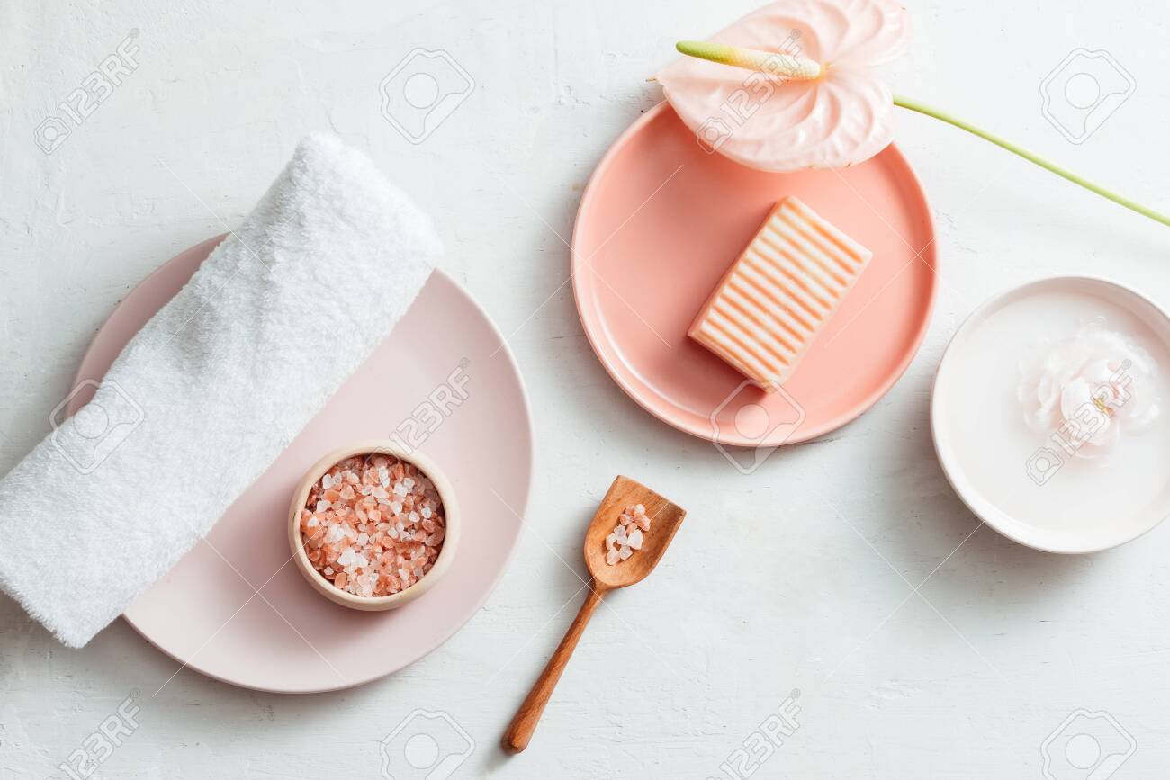 Top view of spa setting with soap, towel, salt and flower on white background - 127065048 Top view of spa setting with soap, towel, salt and flower on white background - 127065048
