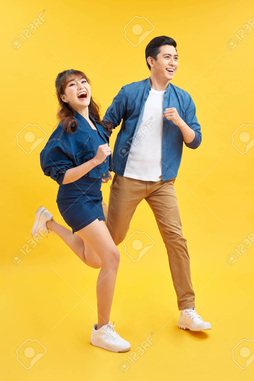 Attractive smiling young Asian couple being happy and amazed isolated on yellow studio background - 139673175 Attractive smiling young Asian couple being happy and amazed isolated on yellow studio background - 139673175