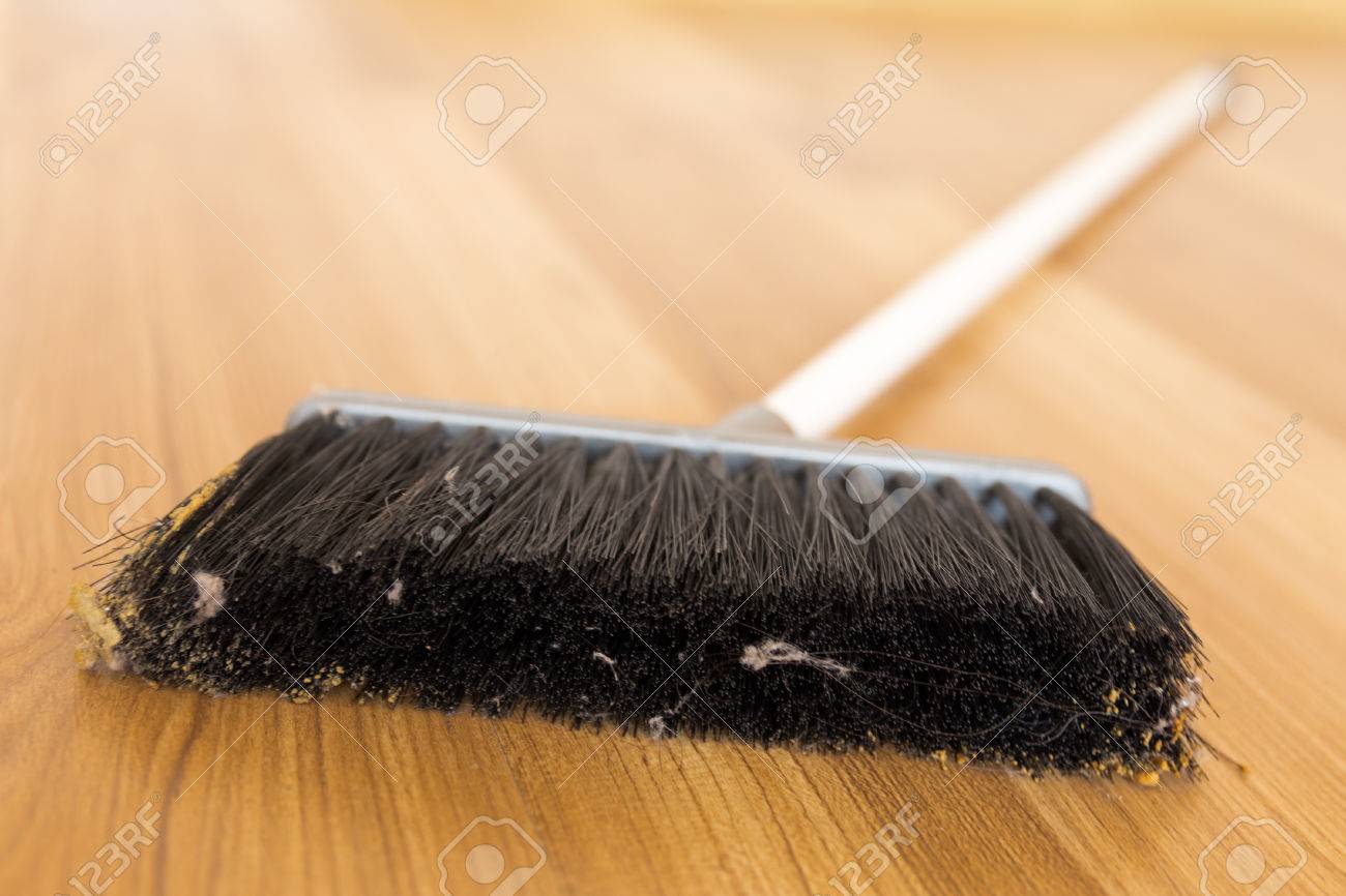 sweeping dust with black broom on a wooden floor stock photo sweeping dust with black broom on a wooden floor stock photo