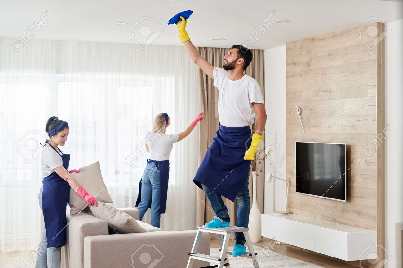 Professional Cleaning Service Team Cleans Living Room In Modern Apartment Stock Photo, Picture and Royalty Free Image. Image 155985942.