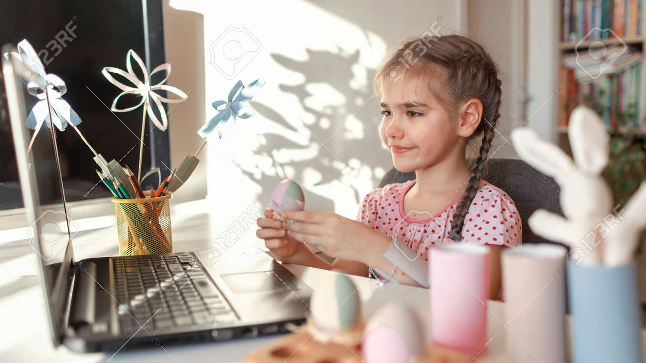 Girl demonstrating DIY flowers, wreath, eggs and greeting with spring holidays her family via internet, online Eater celebration, zero waste, craft for kids, new normal and social distance - 165694901 Girl demonstrating DIY flowers, wreath, eggs and greeting with spring holidays her family via internet, online Eater celebration, zero waste, craft for kids, new normal and social distance - 165694901