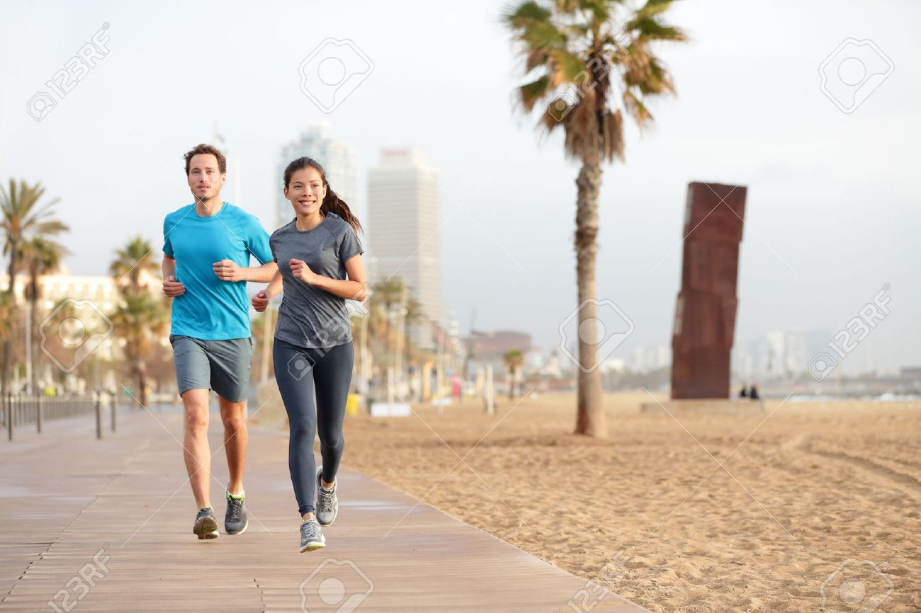 Running couple jogging on Barcelona Beach, Barceloneta. Healthy lifestyle people runners training outside on boardwalk. Multiracial couple, Asian woman, Caucasian fitness man working out, Spain. - 26735503 Running couple jogging on Barcelona Beach, Barceloneta. Healthy lifestyle people runners training outside on boardwalk. Multiracial couple, Asian woman, Caucasian fitness man working out, Spain. - 26735503