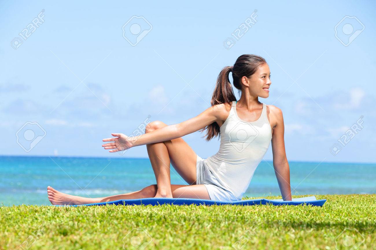 女性ヨガの足のストレッチを行使する海海外フィットネス トレーニング 運動後のストレッチ運動をやっている草の上に座って美しいフィット女性少女モデル 混合レース アジア女性モデル の写真素材 画像素材 Image