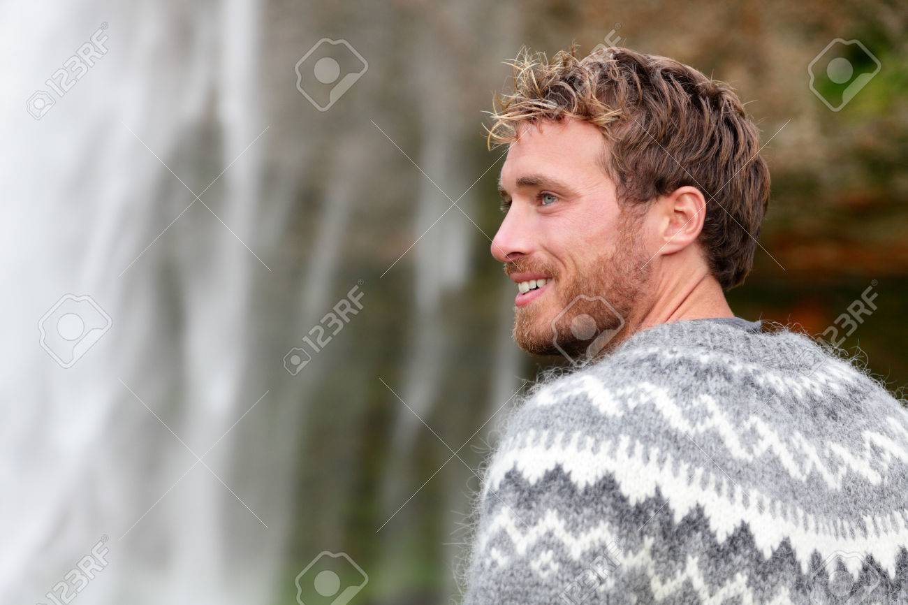 Handsome Man In Icelandic Sweater Outdoor Smiling By Waterfall On Iceland.  Portrait Of Good Looking Male Model Looking To Side In Nature. Фотография,  картинки, изображения и сток-фотография без роялти. Image 32707671