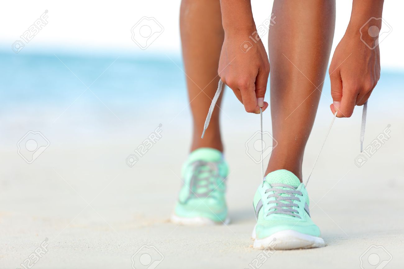 Runner woman tying laces of running shoes preparing for beach jogging. Closeup of hands lacing cross training sneakers trainers for cardio workout. Female athlete living a fit and active life. - 53759567 Runner woman tying laces of running shoes preparing for beach jogging. Closeup of hands lacing cross training sneakers trainers for cardio workout. Female athlete living a fit and active life. - 53759567
