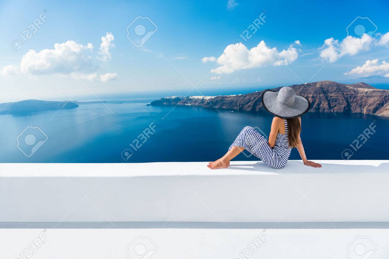 Europe Greece Santorini travel vacation. Woman looking at view on famous travel destination. Elegant young lady living fancy jetset lifestyle wearing dress on holidays. Amazing view of sea and Caldera - 55657498 Europe Greece Santorini travel vacation. Woman looking at view on famous travel destination. Elegant young lady living fancy jetset lifestyle wearing dress on holidays. Amazing view of sea and Caldera - 55657498