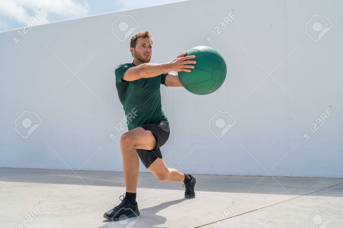Working out man training legs and core ab workout doing lunge twist exercise with medicine ball weight. Gym athlete doing lunges and torso rotations for abs training. - 96290976 Working out man training legs and core ab workout doing lunge twist exercise with medicine ball weight. Gym athlete doing lunges and torso rotations for abs training. - 96290976
