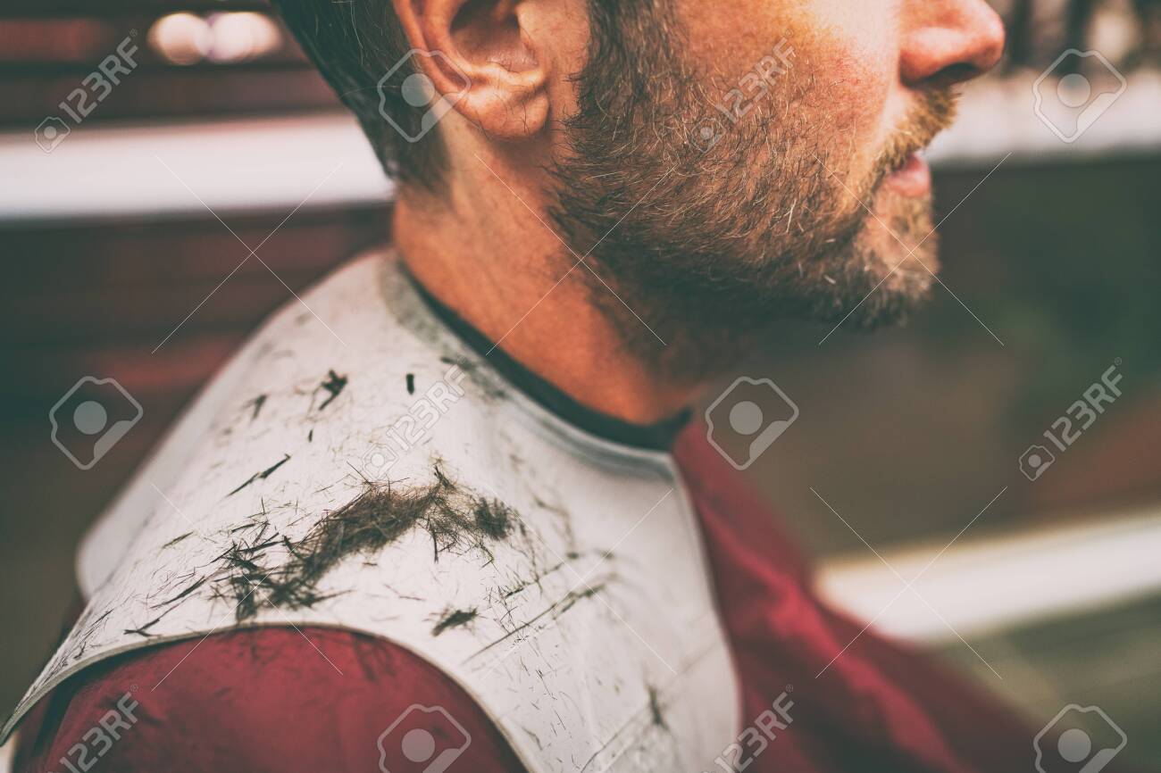 Freshly Cut Hair Fallen On Shoulders Of Man Getting Haircut At