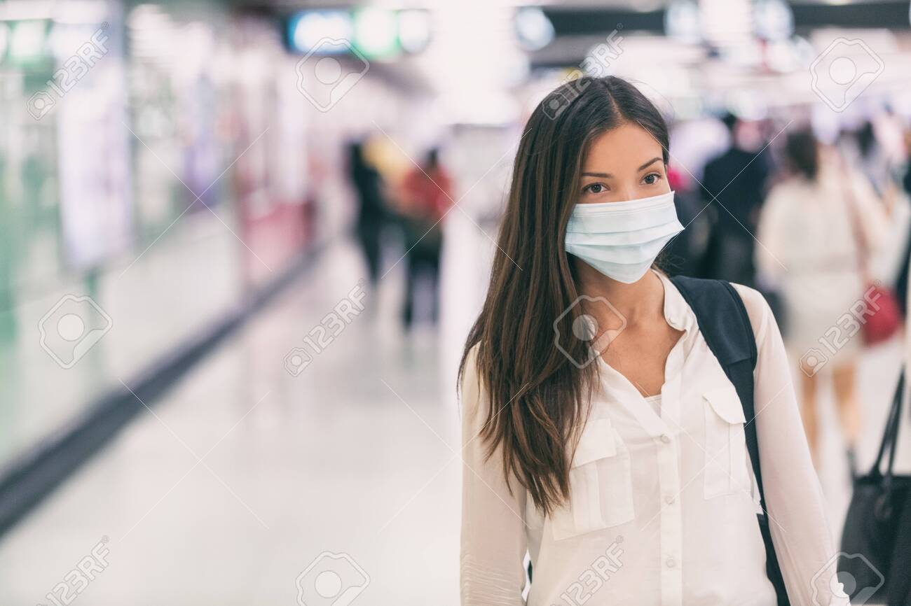Coronavirus Asian woman walking with surgical mask face protection walking in crowds at airport train station work commute to hospital. - 139898510 Coronavirus Asian woman walking with surgical mask face protection walking in crowds at airport train station work commute to hospital. - 139898510
