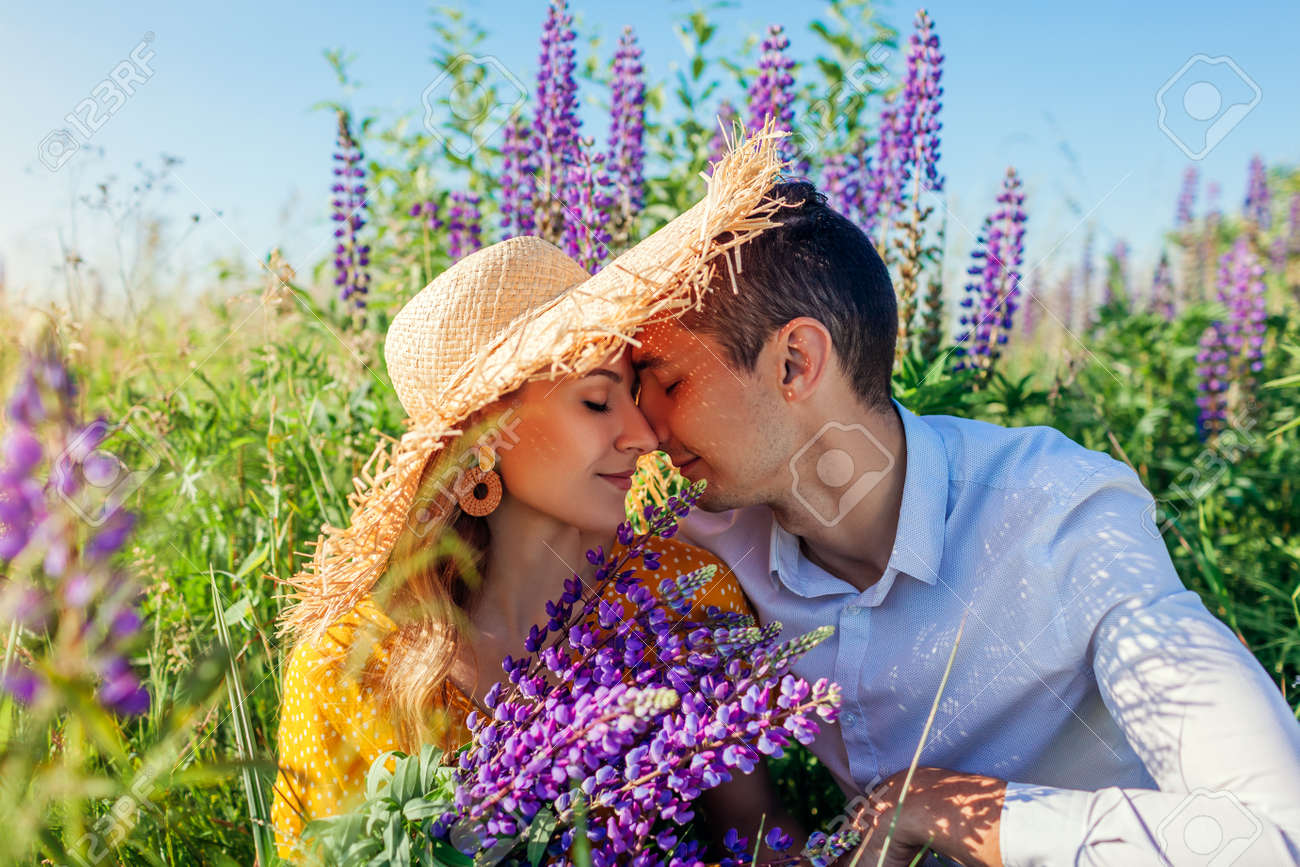 Loving couple hugging in lupin field with bouquet of flowers. Happy man and woman relaxing on meadow. Summer vacation - 171093081 Loving couple hugging in lupin field with bouquet of flowers. Happy man and woman relaxing on meadow. Summer vacation - 171093081