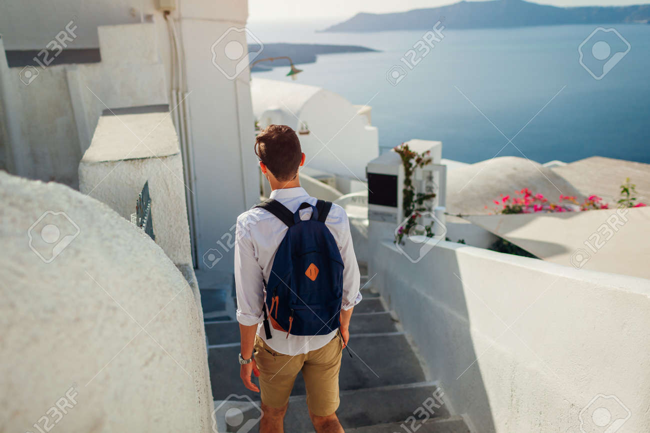 Santorini traveler man walking along narrow street in Fira, Greece enjoying sea view. Tourism, summer vacation - 171282533 Santorini traveler man walking along narrow street in Fira, Greece enjoying sea view. Tourism, summer vacation - 171282533