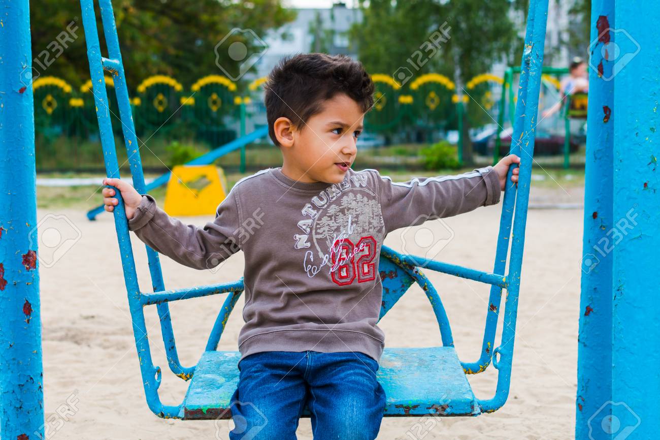 Dark Haired Boy Swinging On A Swing