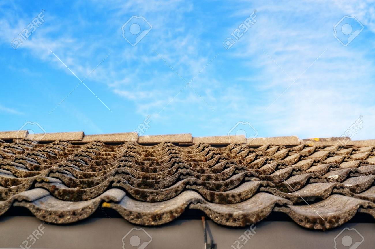 青空を背景にあるタブをグレーのタイルで屋根 グレーのタイルは ノルウェーの夏の別荘の傾斜した屋根のコケで覆われています 目に見える赤い 木製の壁 苔でタイルの端 青い空を背景の屋根 の写真素材 画像素材 Image