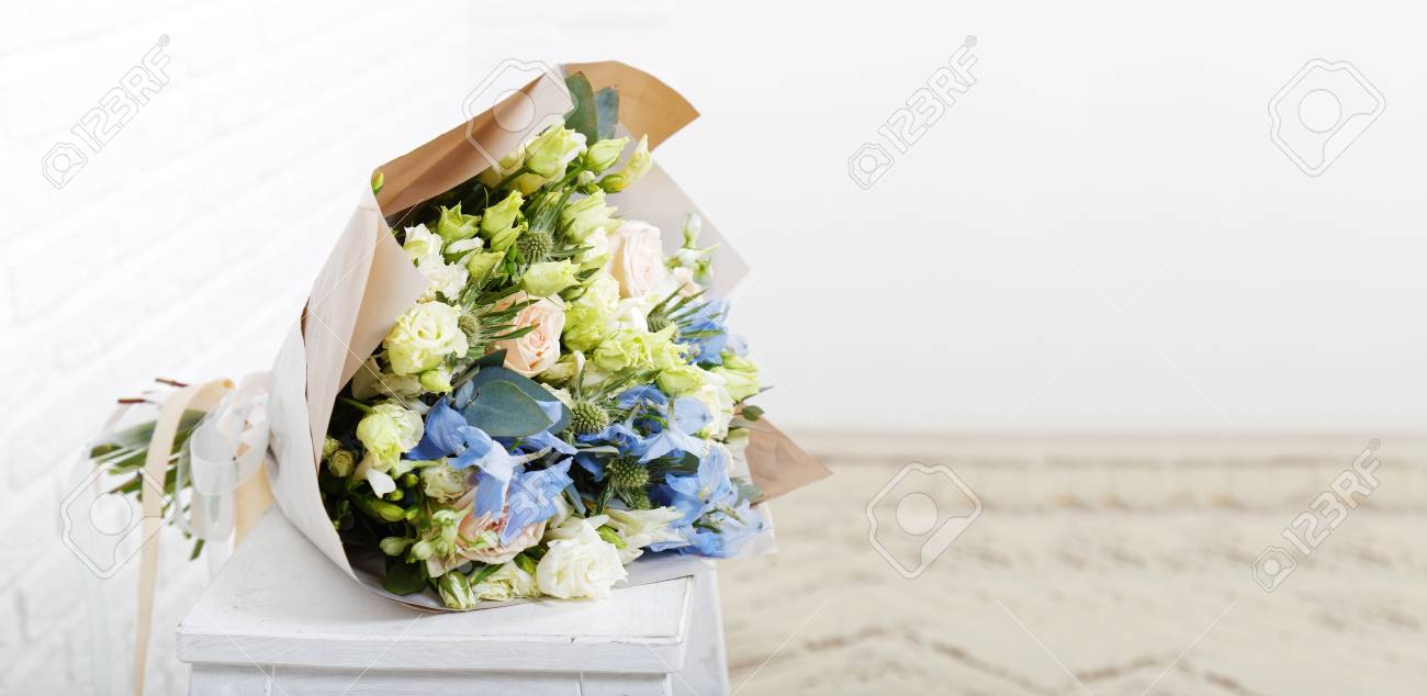 closeup bouquet of flowers in a paper wrap on a white wooden stock flower paper wrap