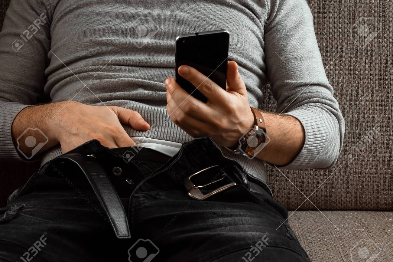 A Man Watches An Adult Video On A Phone While Sitting On A Couch. The  Concept Of Porn, Masturbation, Male Needs, Pervert, Lust, Desire,  Loneliness. Stock Photo, Picture and Royalty Free Image.