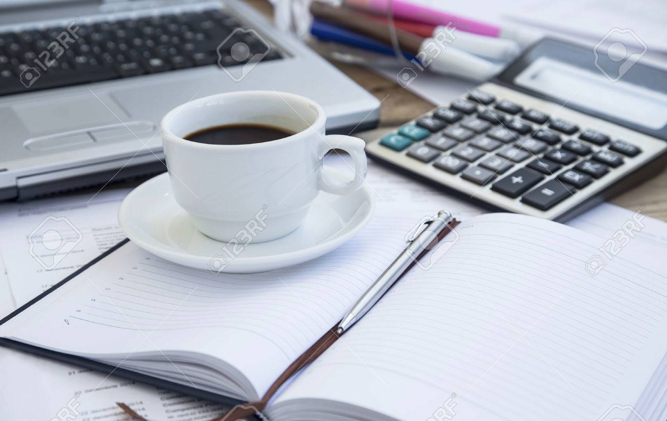coffee cup at office with paperwork agenda and pen calculator office agenda