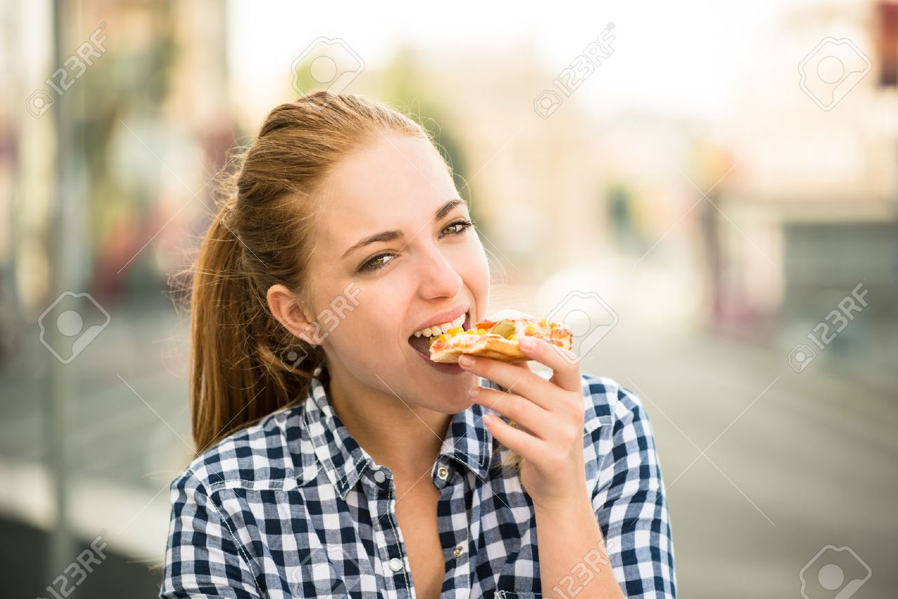 Teenager lifestyle - young woman eating pizza outdoor in street - 51640454 Teenager lifestyle - young woman eating pizza outdoor in street - 51640454