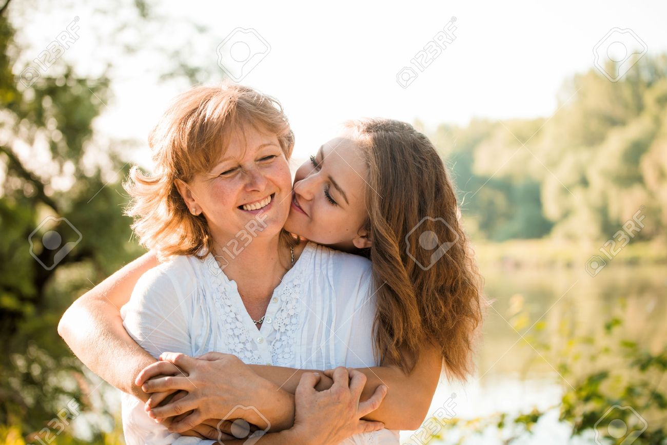 Mature mother hugging with her teen daughter outdoor in nature on sunny day - 52579542 Mature mother hugging with her teen daughter outdoor in nature on sunny day - 52579542