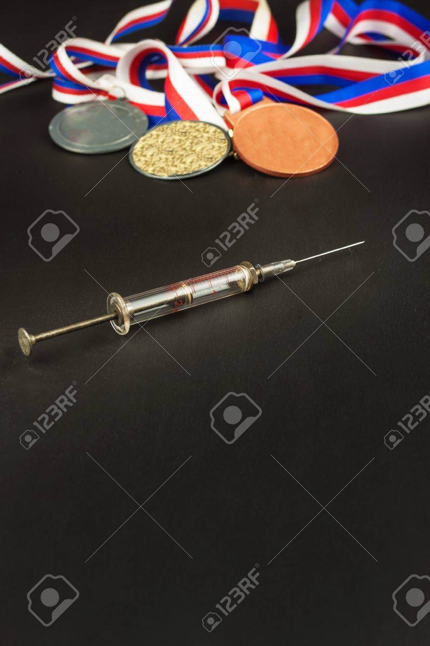 注射器とメダル スポーツのドーピング 蛋白同化ステロイドのスポーツの悪用 蛋白同化ステロイドは 木製のテーブルにこぼした スポーツの詐欺 の写真素材 画像素材 Image