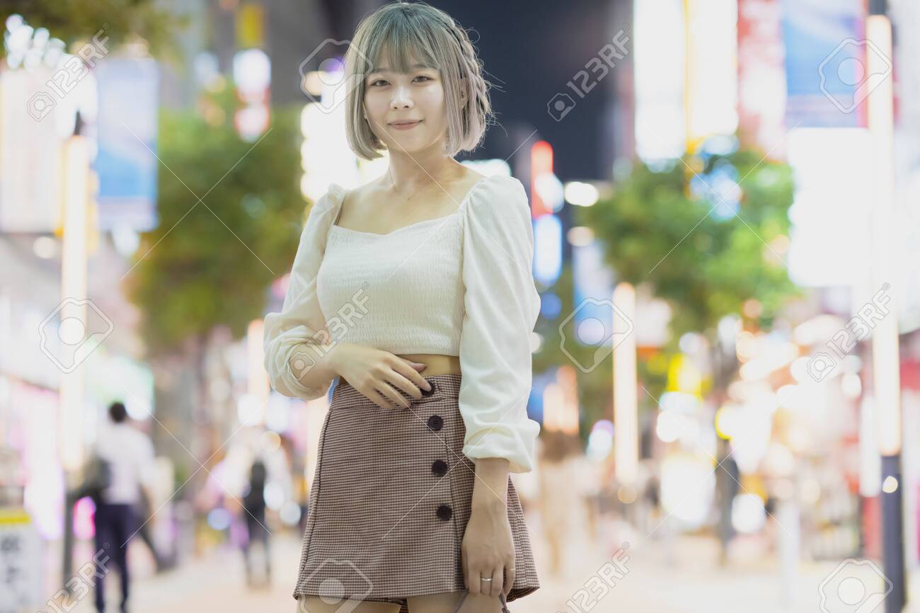 Young woman posing in the glowing cityscape of Tokyo at night - 153412306 Young woman posing in the glowing cityscape of Tokyo at night - 153412306