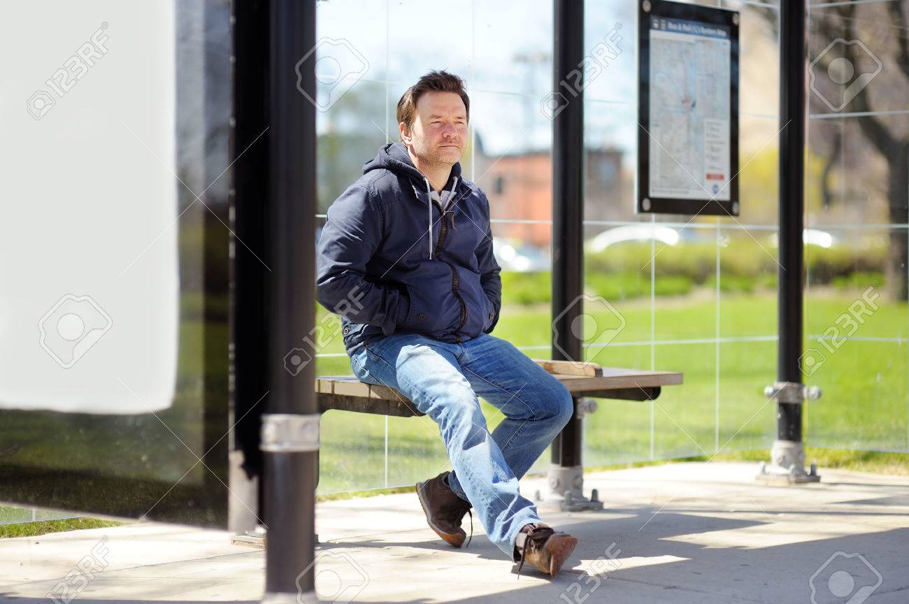 Middle age man sitting on bench on bus stop - 53289699 Middle age man sitting on bench on bus stop - 53289699