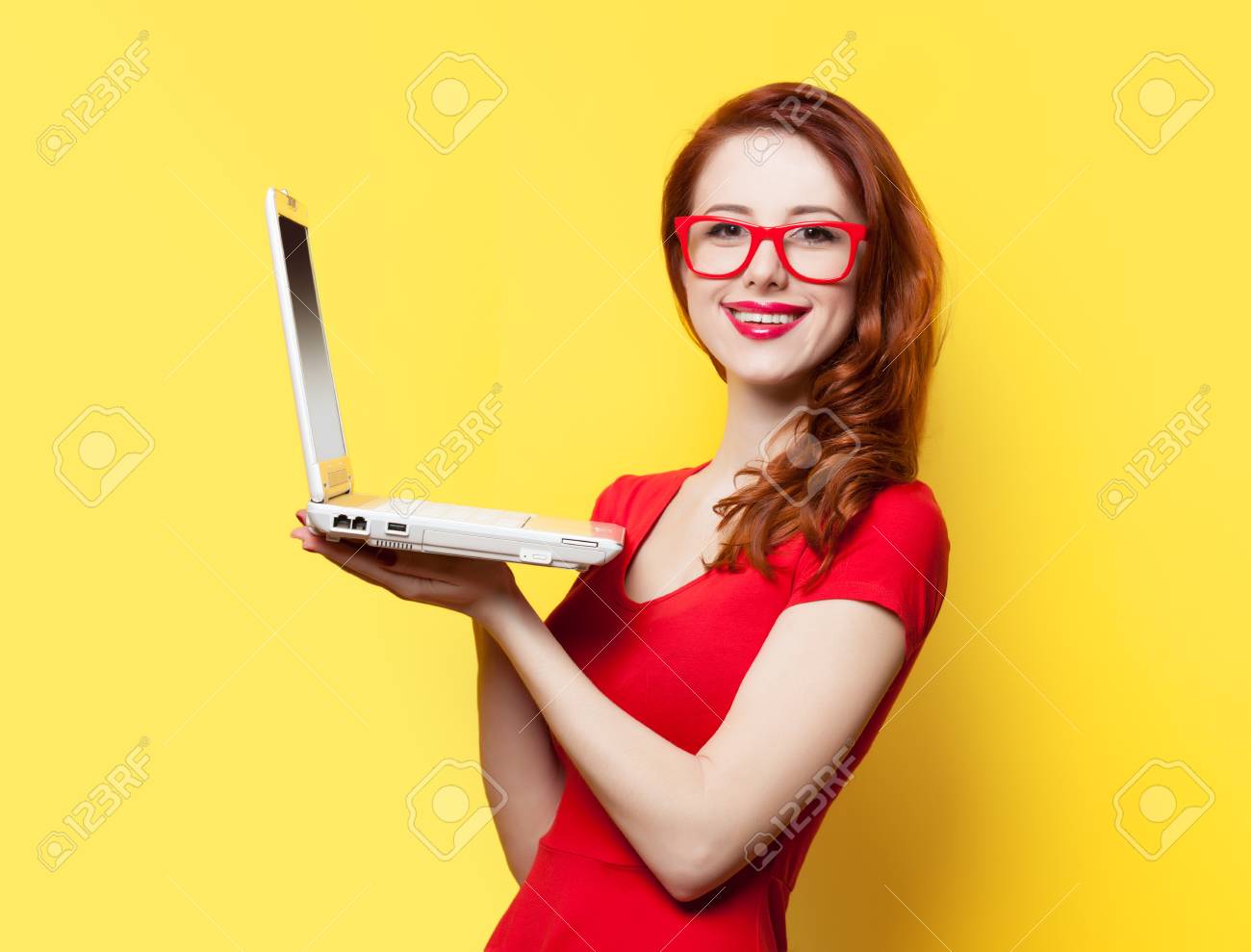 Smiling redhead girl with laptop on yellow background - 37324379 Smiling redhead girl with laptop on yellow background - 37324379