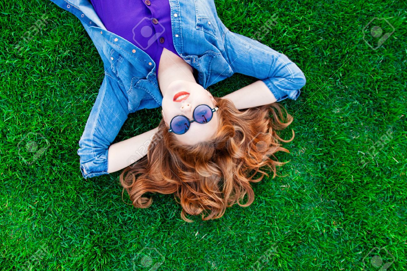 Beautiful redhead women lying down on green grass in summer time in the park. - 40044504 Beautiful redhead women lying down on green grass in summer time in the park. - 40044504